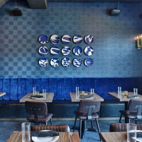 Fanny's restaurant interior with blue textured walls, velvet banquettes, and patterned decorative plates.