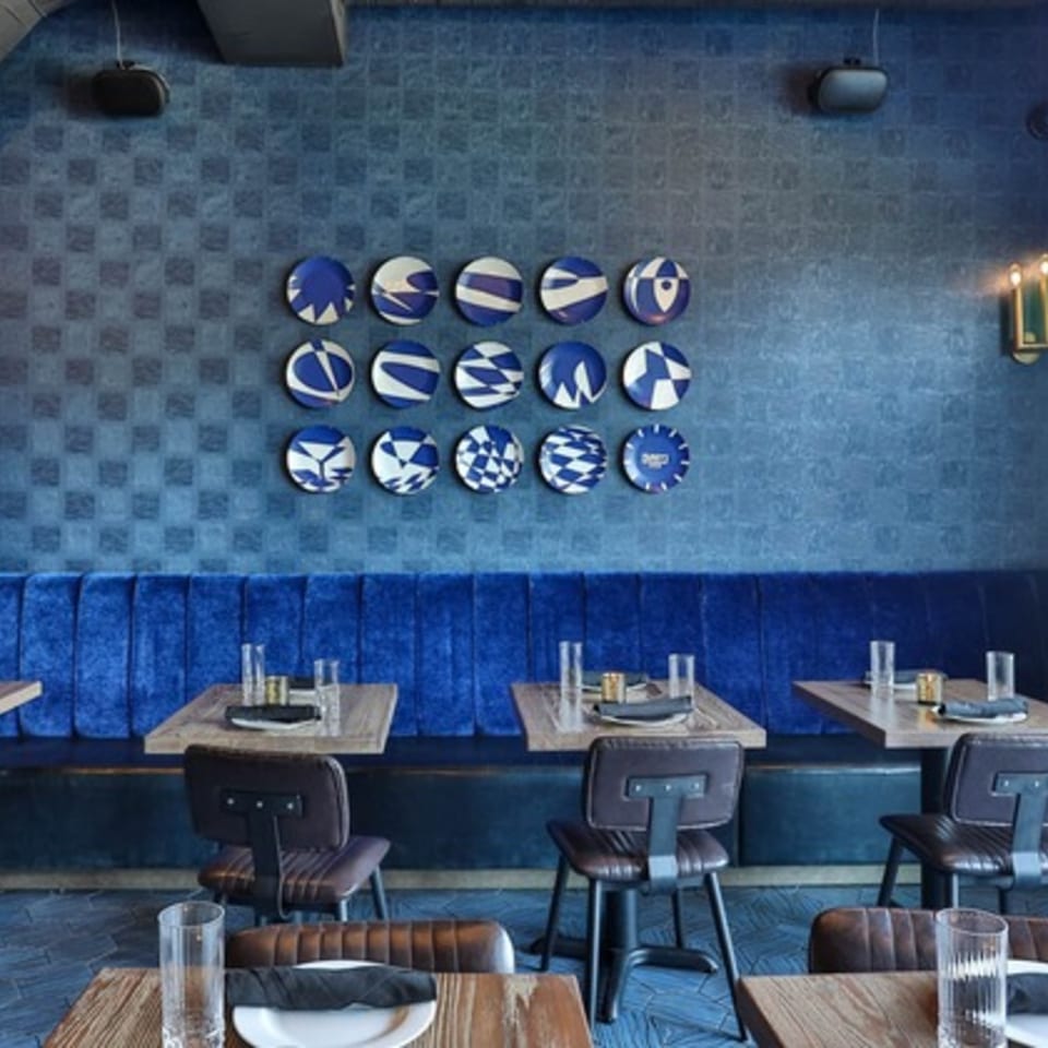 Fanny's restaurant interior with blue textured walls, velvet banquettes, and patterned decorative plates.