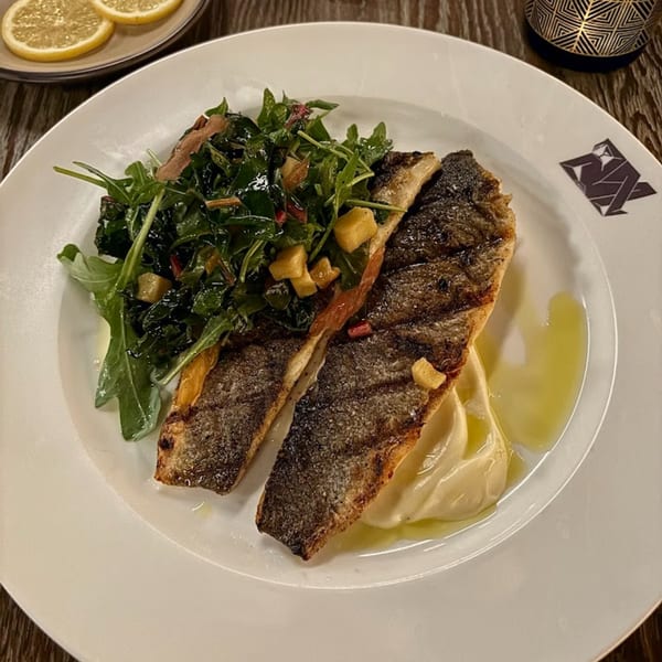Pan-seared fish with crispy skin, served with a side of green salad and creamy mashed potatoes.