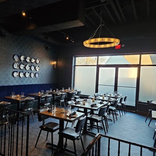 Fanny's Italian restaurant interior with dark walls, blue banquettes, and set tables.