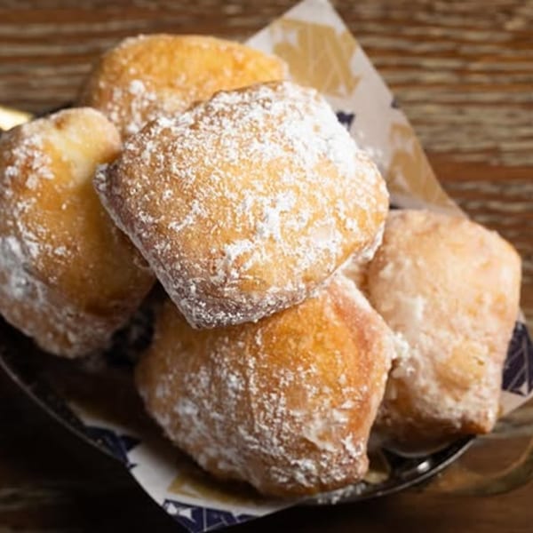 A close-up of Fanny's Italian zeppole, golden-brown and generously dusted with powdered sugar.